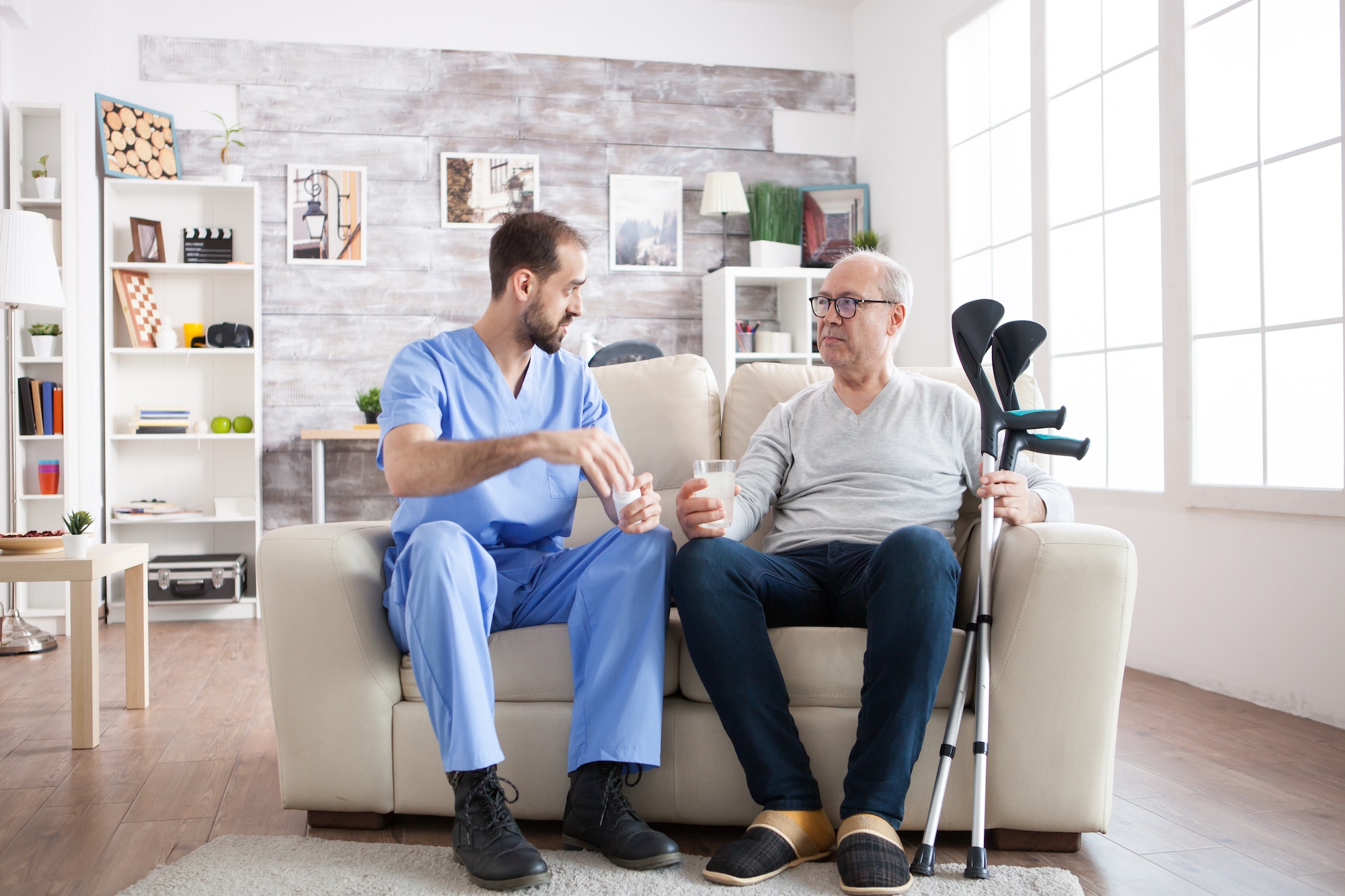 young-male-nurse-in-nursing-home-with-pills-for-senior-man.jpg